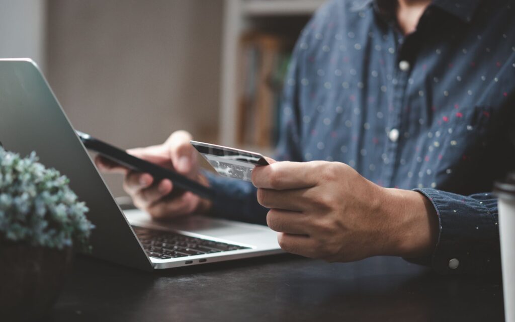 persona al computer con carta di credito in mano