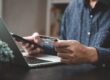 persona al computer con carta di credito in mano